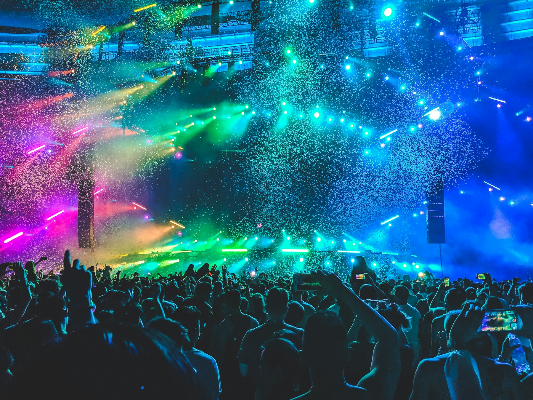 Large crowd beneath colorful concert lighting